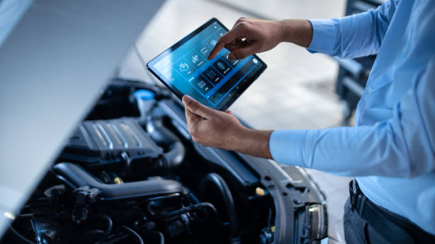 istock Car Service Manager or Mechanic Uses a Tablet Computer with a Futuristic Interactive Diagnostics Software. Specialist Inspecting the Vehicle in Order to Find Broken Components In the Engine Bay. 1220306180