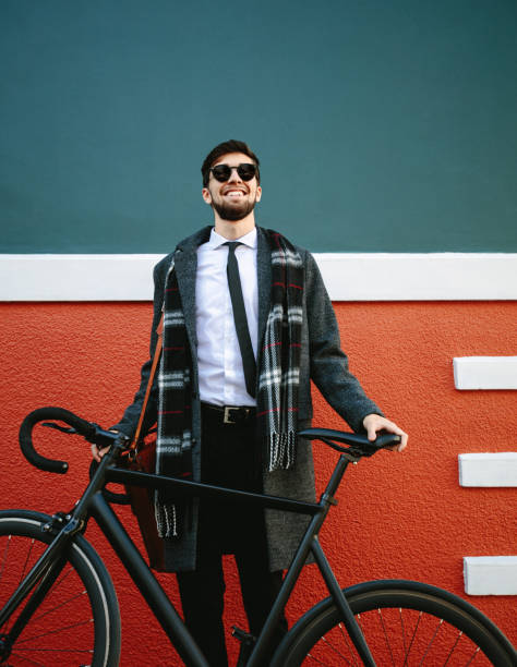 Smiling man going to work by bicycle. Businessman standing by his bike on sidewalk outdoors.