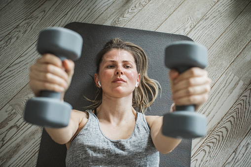 Women at home during pandemic isolation doing workout with weights to stay in shape