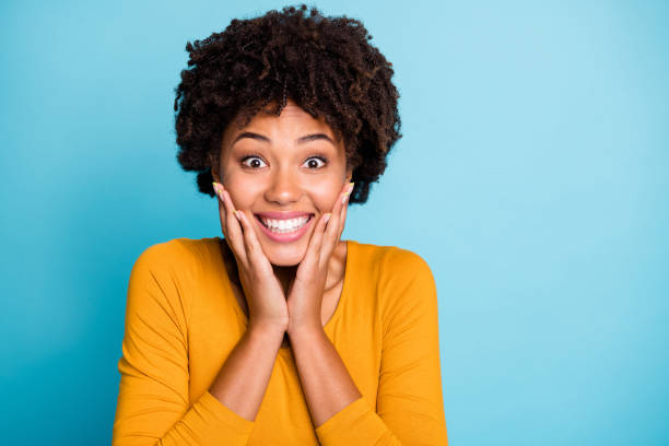 Omg i cant believe. Close up photo enthusiastic cheerful afro american girl wait long expected wish present touch hands face wear style stylish trendy sweater isolated blue color background Omg i cant believe. Close up photo enthusiastic cheerful afro american girl wait long, expected wish present touch hands face wear style stylish trendy sweater isolated blue color background excited woman yellow stock pictures, royalty-free photos & images