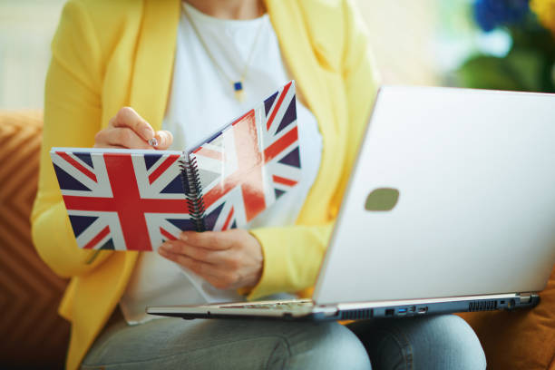 istock trendy female with laptop taking notes in UK flag notebook 1220316658