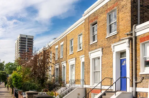 A series of brick-built terraced houses, with a tower block in the distance.