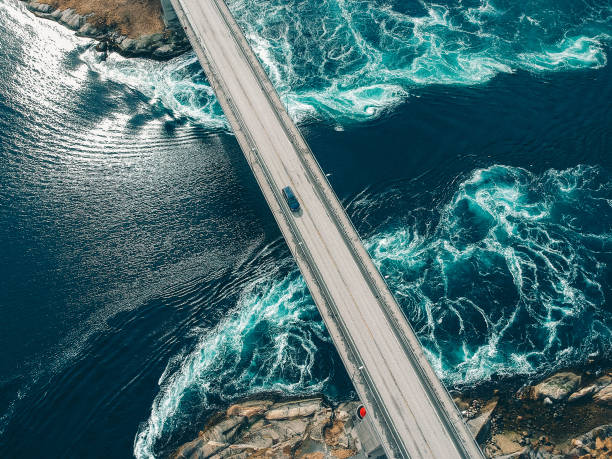 Car traversing bridge with water torrents beneath Torrents creating patterns in turquoise water underneath a bridge with a car traveling across it at Salstraumen near Bodo Norway fuel and power generation photos stock pictures, royalty-free photos & images