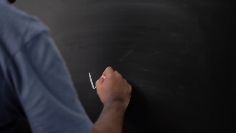 Close up male hand writing check mark with chalk on chalkboard.