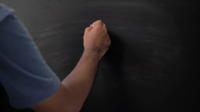Close up male hand drawing smile emotion icon with chalk on chalkboard.
