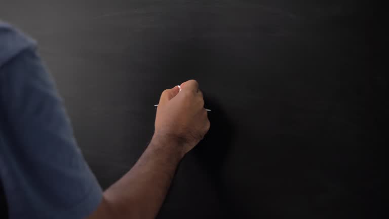 Close up male hand drawing divide symbol with chalk on chalkboard.