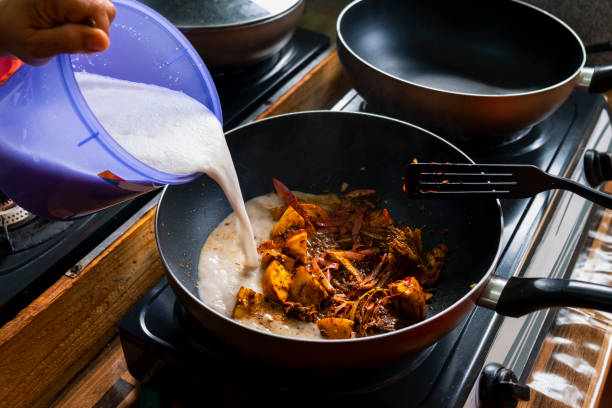 Malaysian Cuisine Experience An image of a pan with Malaysian vegetarian food cooking as coconut milk is pored into the pan. coconut milk stock pictures, royalty-free photos & images