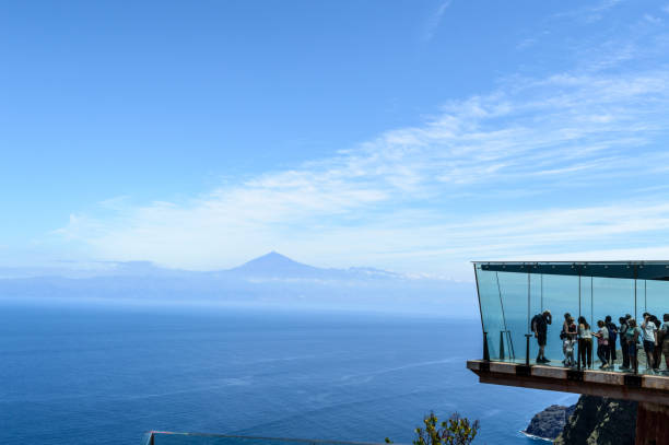 Abrante Glass Lookout With Teide Background On La Gomera Island With Several Unrecognizable People Looking Through The Glazed Lookout. Abrante Glass Lookout With Teide Background On La Gomera Island With Several Unrecognizable People Looking Through The Glazed Lookout. April 15, 2019. La Gomera, Santa Cruz de Tenerife Spain Africa. agulo stock pictures, royalty-free photos & images