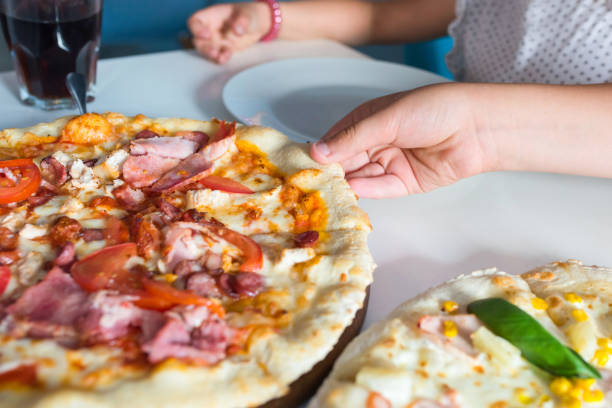 istock Children's hands with a pizza closeup on the table. 1220327275