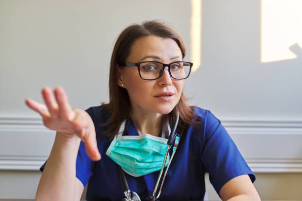 femme parlante de docteur s’asseyant dans le bureau, appel de vidéoconférence - instant camera photos et images de collection