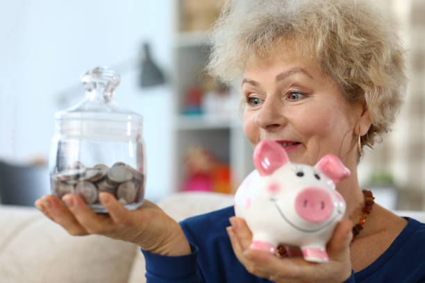 an old lady holding piggy bank and glass jar coins - xxx imagens e fotografias de stock