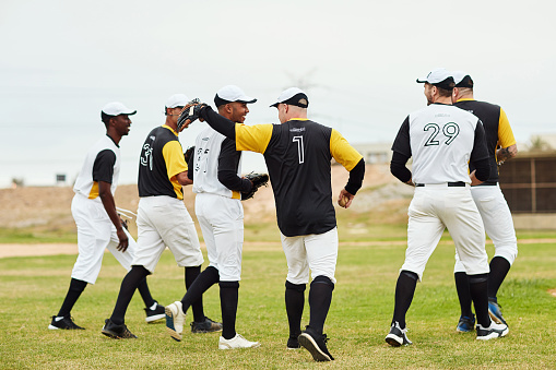 Full length shot of a team of young baseball players walking together on the pitch outdoors