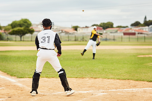 Rearview shot of a young baseball player getting ready to catch the ball during a game outdoors