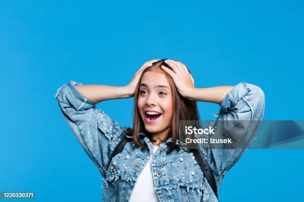 Portrait Of Excited Teenage Girl Against Blue Background Stock Photo - Download Image Now