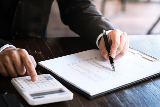 istock Businessman analyzing investment charts and pressing calculator buttons over documents. Accounting Concept. 1220330441