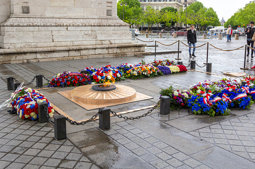 Paris, France - May 8, 2019: Flowers and eternal flame near Arc de Triomphe in honor of victory over fascism in World War II on Place de Gaulle in Paris, France