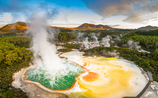 Aerial footage of hot sulphur springs at sunrise, showing colour splashed geothermal reserve of boiling water and steam evaporating in North Island of New Zealand