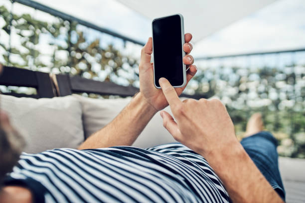 istock Close up of man using smartphone while lounging on apartment terrace 1220334866