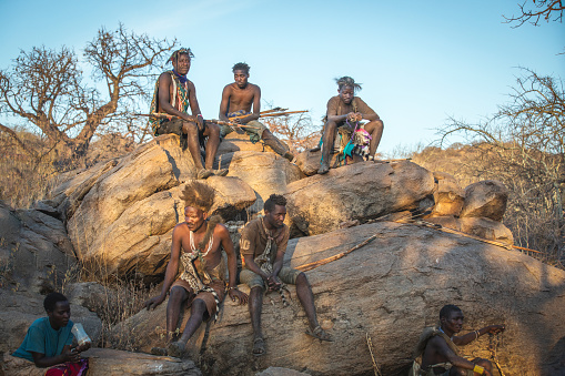 Lake Eyasi, Tanzania, 11th September 2019: Hadzabe men resting on a rock in a evening sun after along hunt