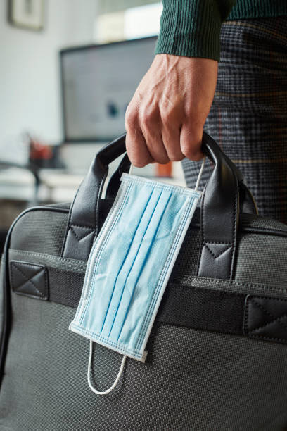 man with a briefcase and a surgical mask closeup of a young man in an office holding a briefcase and a surgical mask in his hand only young men stock pictures, royalty-free photos & images