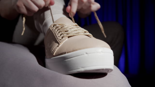 Woman is tying shoelaces of her sneakers