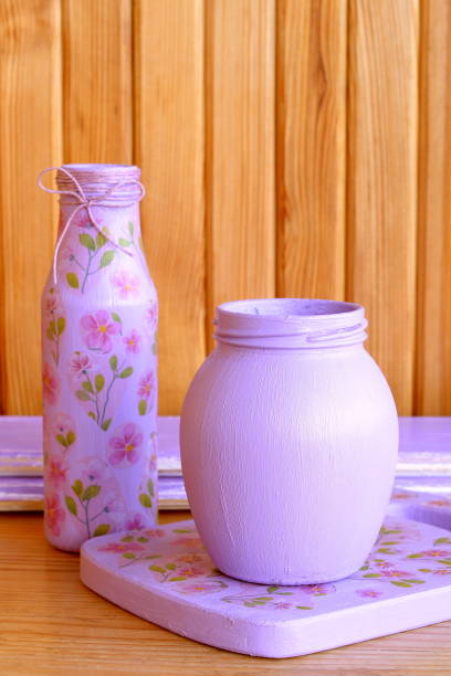 colored glass bottle and cutting board. handmade decoupage bottle with flower pattern. decoupage on wooden chopping board. art and craft idea to create kitchen decor. recycled projects - flower pot vase purple decor imagens e fotografias de stock