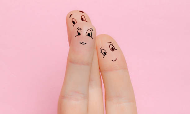 trois doigts avec des visages peints d’un homme et d’une femme et des enfants sourient et se réjouissent dans le fond rose isolé. le concept d’une famille d’amour et de relations sans personnes - three objects flash photos et images de collection