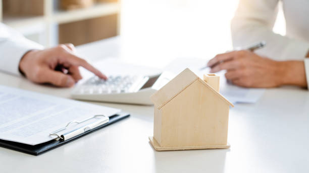 istock Cropped Hands With Model Home On Desk 1220339894