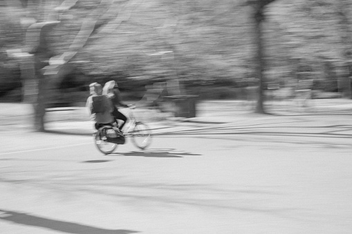 Motion blur of a cyclist and pillion passenger in Vondelpark, Amsterdam, Netherlands