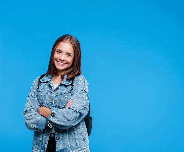 glücklich teenege mädchen mit armen auf blauem hintergrund gekreuzt - jacket child clothing fashion stock-fotos und bilder