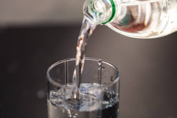 istock Pouring water from plastic bottle into a glass on blurred background. Selective focus and copy space 1220343162
