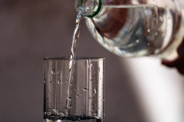 istock Pouring water from plastic bottle into a glass on blurred background. Selective focus and copy space 1220343187