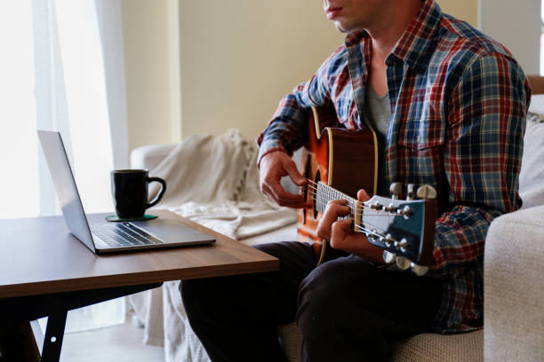 음악 개념의 온라인 학교. 집에서 어쿠스틱 기타를 누워 배우는 남자. - fingerstyle 뉴스 사진 이미지