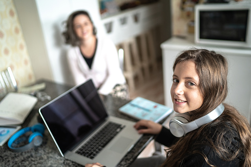 Portrait of girl using laptop at home - mother on background