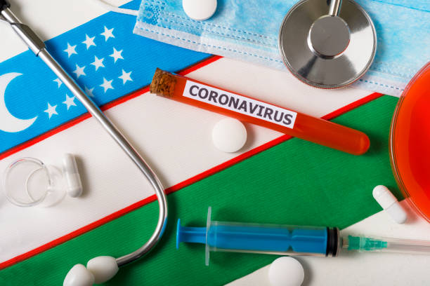 istock Coronavirus, nCoV concept. Top view protective breathing mask, stethoscope, syringe, pills on the flag of Uzbekistan. 1220347251