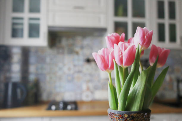 a bouquet of pink tulips on a background of bright kitchen. place for text. - tulip vase flower spring imagens e fotografias de stock