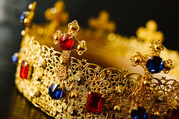 Golden crown encrusted with blue and red gemstones on a black background