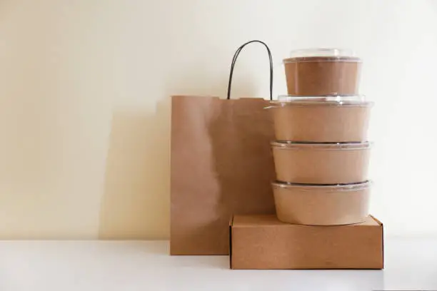 Photo of Stacks of ordered food and croceries in paper takeout containers and bags on table.