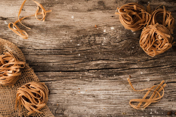 pasta on a wooden table - homemade pasta lying on a wooden, rustic table.