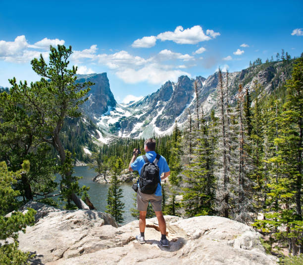 istock Hiker standing on top of the mountain using his camera. 1220352401