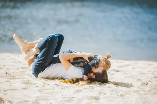 istock A happy father playing with young son at the sandy beach. Side view 1220354890