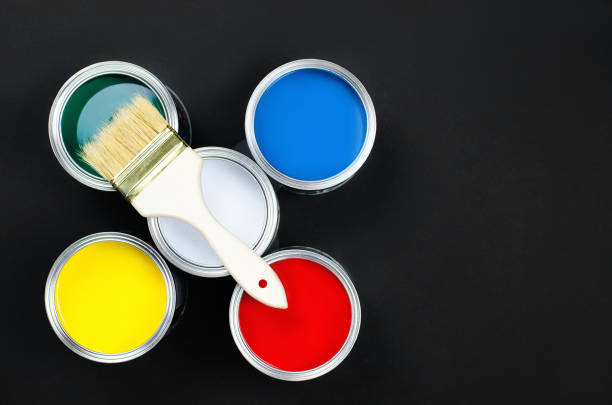 istock Five multi-colored cans with paint and a brush on a black background. 1220355196