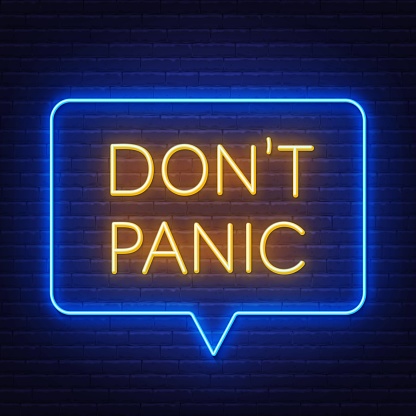 Don't panic neon lettering on brick wall background .