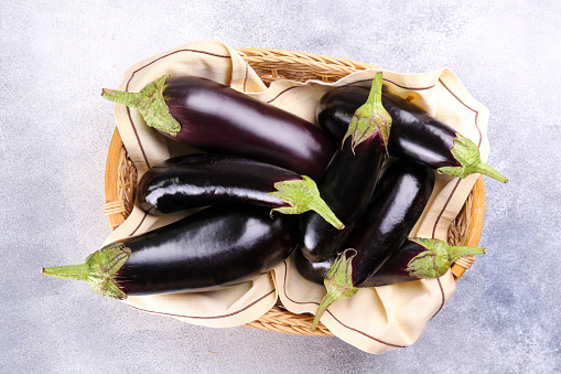 Bunch of ripe organic polished eggplants laid in composition on grunged stone background. Aubergine vegetables at table counter. Clean eating concept. Background, close up, flat lay, top view.