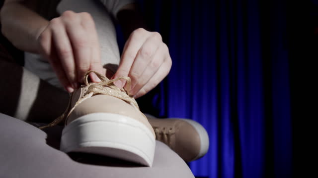 Woman is tying shoelaces of her sneakers