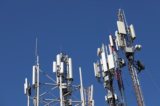 Many mobile towers, satellites and repeaters on a background of blue sky. Wireless communication equipment.