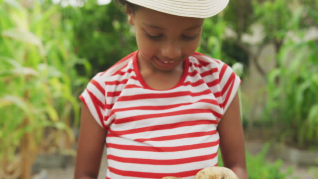 African American girl showing potatoes at the camera