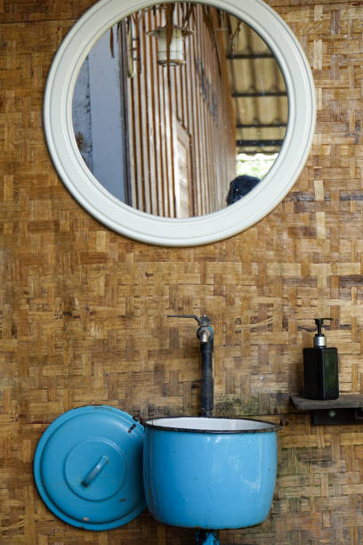 istock hotel or accommodation, at hand washing area, there is a blue metal deep pot that used for a basin and a circle mirror over a lavatory. those hang on wooden wall 1220363478