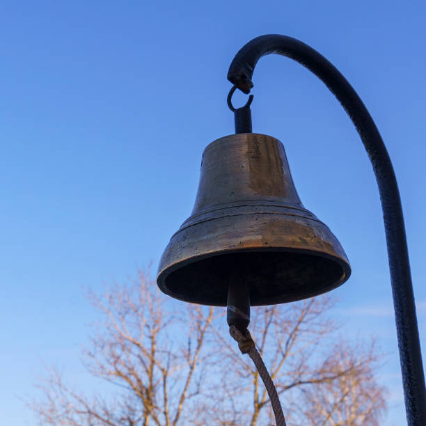 zbliżenie starego dzwonka ogniowego z brązu skool na klasycznym tle błękitnego nieba. koncepcja alarmu pożarowego. - service bell flash zdjęcia i obrazy z banku zdjęć