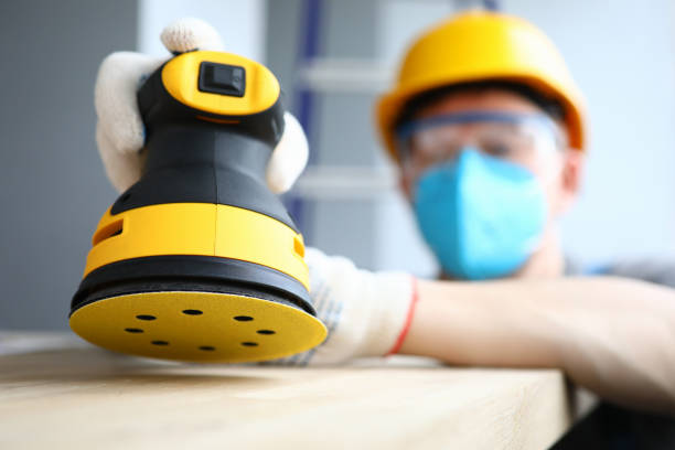 istock Masked builder polishes sander wooden surface 1220365425